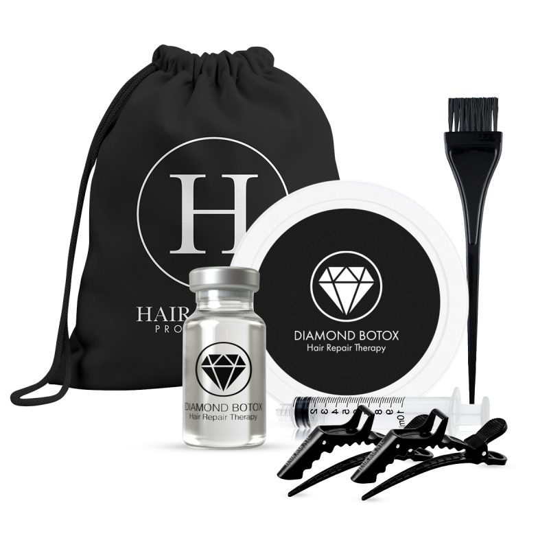 A black drawstring bag labeled Diamond Bottox Hair Repair Home Kit stands behind a vial, round container, brush, syringe, and two clips. Both the vial and container feature a diamond logo with "Diamond Botox Hair Repair Therapy.