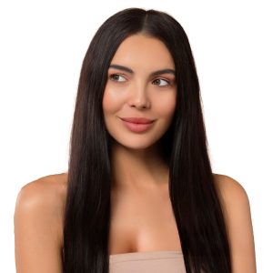 A woman with long, straight, dark brown hair and fair skin smiles softly, wearing a strapless beige top. Her smooth hair showcases the results of the Silk Touch Express Keratin Treatment against a plain white background.