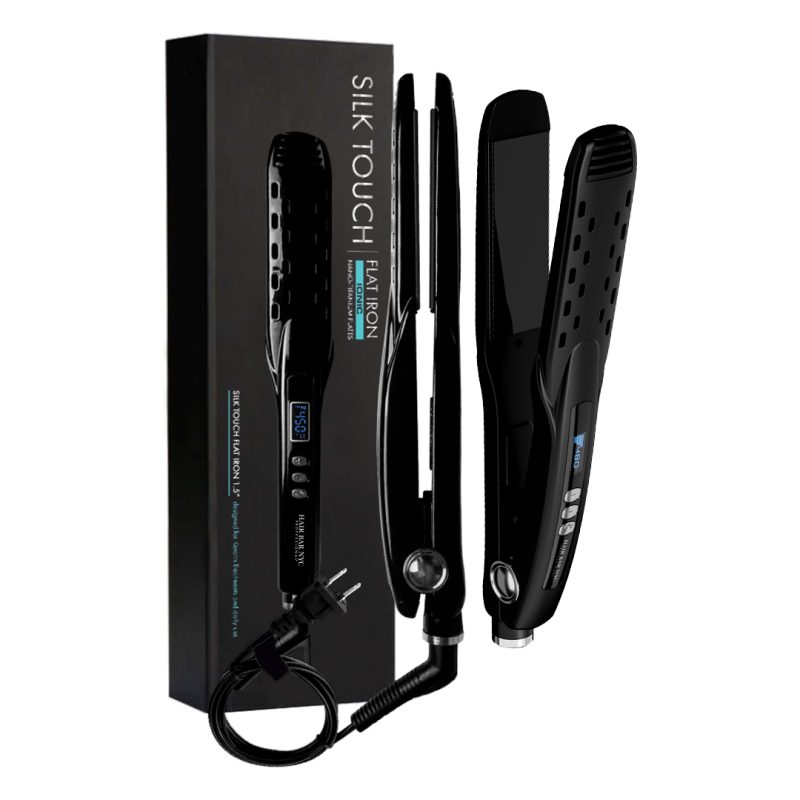 A black Silk Touch Ionic Flat Iron 1.5" with a cord stands upright beside its sleek box, displaying product details in blue and white. The flat iron features a small LCD screen, buttons, and vent holes.