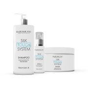 The Silk Touch System Duo Bundle is displayed, featuring a tall shampoo pump bottle, a smaller serum pump bottle, and a wide mask jar. Packaging is white with black and light blue text.